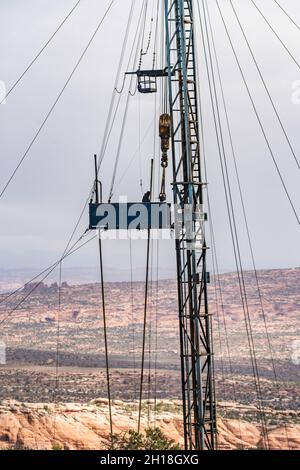 A derrickman or derrickhand on the tubing board on the mast of a workover rig on an oil well in Utah. Stock Photo