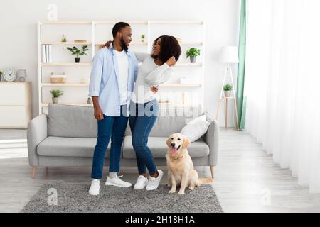 Young black couple hugging at home with dog Stock Photo