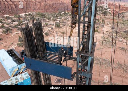 The derrickman attaches tubing to the traveling block on a workover rig doing maintenance on an oil well. Stock Photo