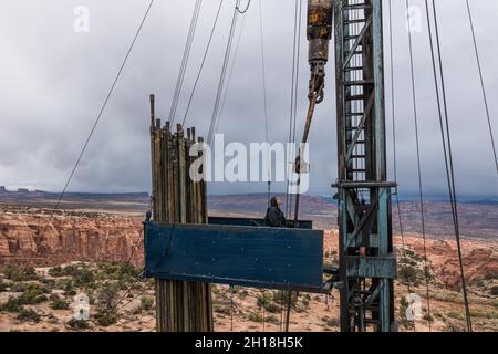 The derrickman attaches tubing to the traveling block on a workover rig doing maintenance on an oil well. Stock Photo