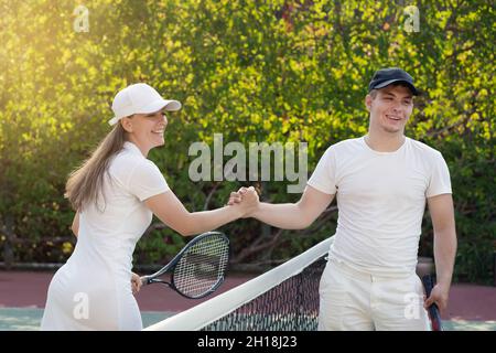 handshake after a tennis match played, a white young man and a woman. brother and sister played a game of tennis. Stock Photo