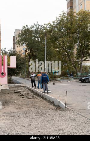 Tiraspol, Moldova - October 15, 2021: Road service workers install new concrete curbs in the courtyard of an apartment building in the capital of the Stock Photo