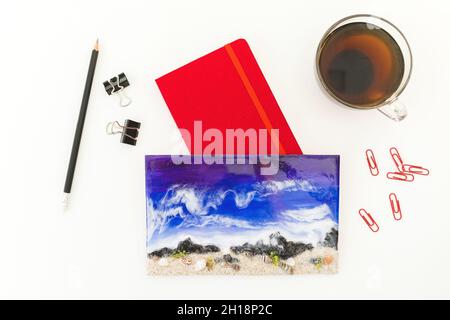 Resin art with red diary, clips, pencil and cap of tee on white background. Flat lay, Top view Stock Photo