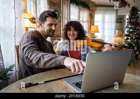 Private male music teacher giving violin lessons to a woman at home Stock Photo