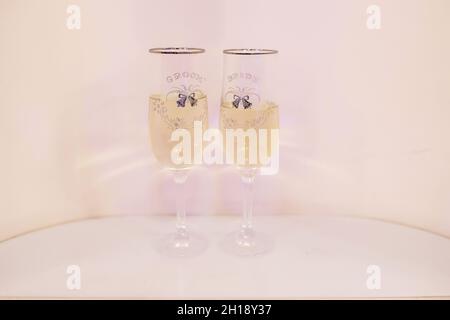 Two ornate champagne flutes with message "groom" and "bride" and thin black ink decoration, elegant wedding reception recipients used by the newlyweds Stock Photo