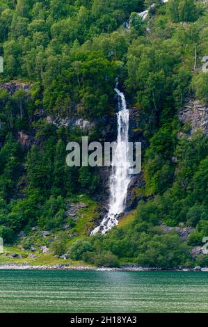 A waterfall plunges off sheer cliffs into Geirangerfjord. Geiranger, Geirangerfjord, Norway. Stock Photo