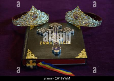 Ritual in preparation for a wedding ceremony in Orthodox religion including a holy book called 'Evanghelie', a silver ornate cross and two crowns Stock Photo