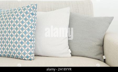Close-up of three different sizes cushions in soft pastel colors, almost monochrome, positioned on a beige, textile sofa, very modern minimalist style Stock Photo