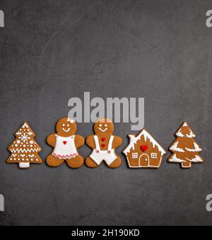 Christmas gingerbread cookies. Man woman and house in a row on a grey background. Top view, flat lay, copy space. Stock Photo