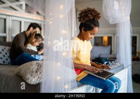 Preteen schoolgirl doing her homework with notebook at home. Child using gadgets to study. Stock Photo