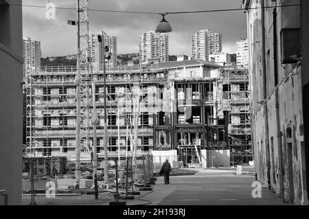 Black and white photo with cranes and ruined public building construction. Urban street in the city