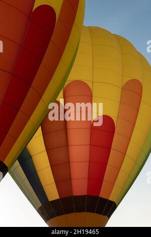 A vertical shot of two hot air balloons in green, blue, red, and yellow colors Stock Photo