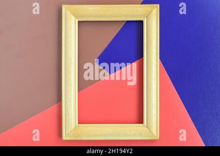 Empty wooden frame made of beech on background of wide colored stripes of different colors. Red, blue, brown. Place for photo. Vertical layout. Mockup Stock Photo