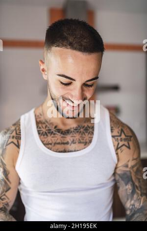A vertical portrait of a smiling tattooed Caucasian fit male Stock Photo