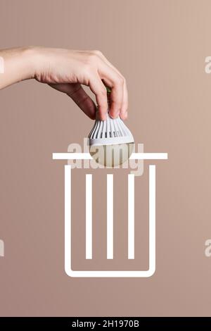 A person throwing light bulb for recycling. Hand throws used light bulb into garbage. Concept of sorting, recycling Stock Photo