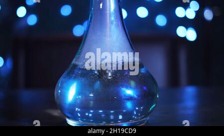 Glass bowl of hookah on the table, traditional East relaxation. Close up of transparent glass flask filled with water and smoke at the night club or b Stock Photo