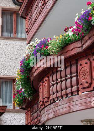 Traditional alpine wooden balcony decorated with flowers, especially typical of German Switzerland and Tyrol. Samnaun, Switzerland, a duty free villag Stock Photo