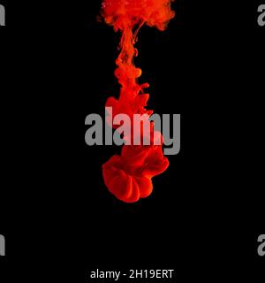 Red acrylic Ink splashes in water on black backdrop. Minimal abstract background. Stock Photo