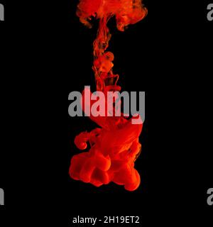 Red acrylic Ink splashes in water on black backdrop. Minimal abstract background. Stock Photo