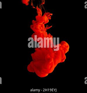 Red acrylic Ink splashes in water on black backdrop. Minimal abstract background. Stock Photo