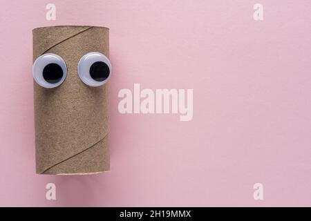 Completed toilet paper roll with googly eyes on pink background. Minimal Coronavirus outbreak. Panic concept. Stock Photo