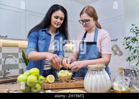 Mom and teenage daughter preparing apple pie together Stock Photo