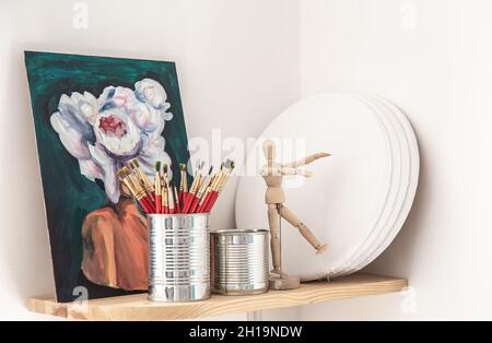 Red brushes for painting in a tin can on a shelf in a workshop. Stock Photo