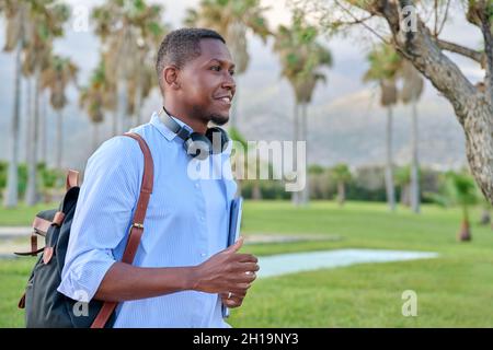 Outdoor portrait of young man with laptop headphones and backpack Stock Photo