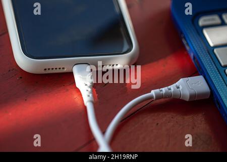 The smartphone is connected to the laptop via USB cable. Stock Photo