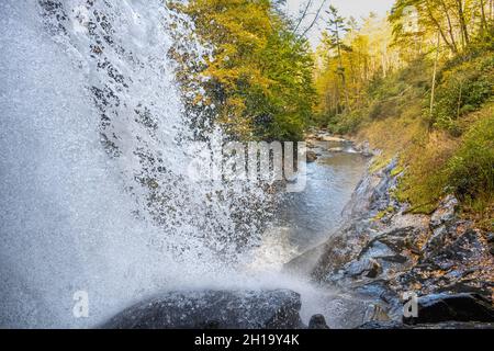 View from behind and to the side of Dry Falls, a walk-behind waterfall between Highlands and Franklin, North Carolina, on a beautiful autumn day. Stock Photo