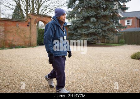 Elderly British Asian woman walking outdoors in winter. May represent senior exercising or life at a UK care home or nursing home. Stock Photo