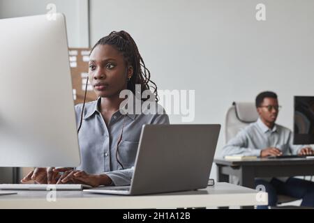 Portrait of two African-American young people using computers while working in software development office, copy space Stock Photo