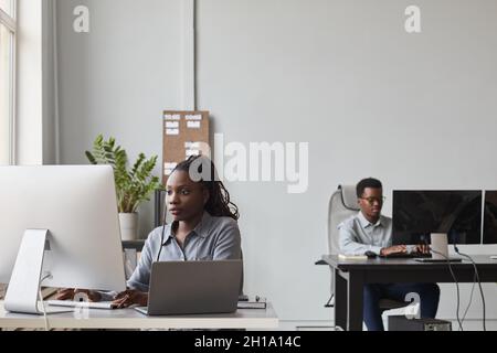 Wide angle portrait of two African-American young people using computers while working in software development office, copy space Stock Photo