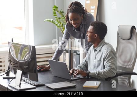 Portrait of two young people looking at computer screen and smiling while enjoying work in software development office, copy space Stock Photo