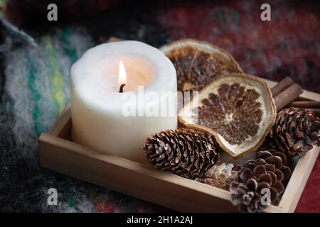 Close-up of a burning candle, pine cones, dried oranges and cinnamon. Stock Photo