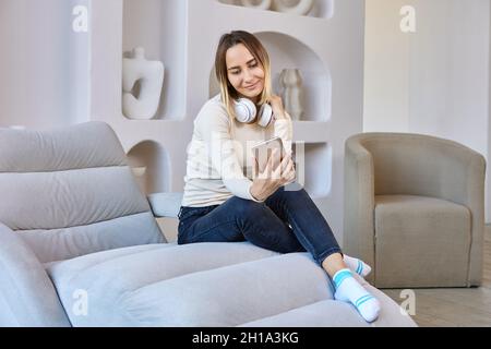 Smiling woman in headphones makes selfie in lounge. Stock Photo