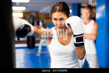 Asian female practicing punches with boxing bag at gym Stock Photo