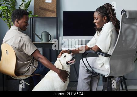 Portrait of smiling young people petting dog while working in pet friendly office, copy space Stock Photo