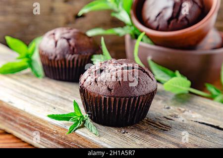 Chocolate cupcake muffin with mint leaves in rustic style. Fresh baked chocolate muffins with no top on dark wooden background.Mint Cupcakes Stock Photo