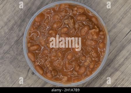 Overhead view of generous portion side order of baked beans in a clear plastic bowl to compliment your meal. Stock Photo