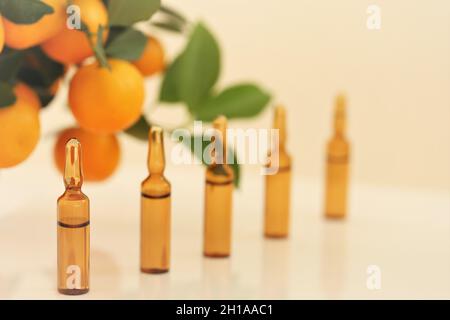 Vitamin C. serum with vitamin C.Glass ampoules and tangerine fruit bushes on beige background.ampoules and Serum with Vitamin C. Organic natural Stock Photo