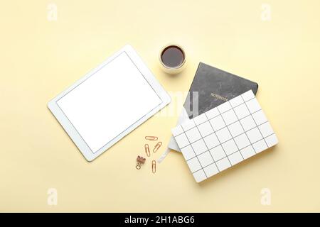 Cup of coffee, tablet computer and stationery on color background Stock Photo