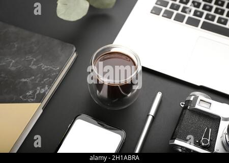 Cup of coffee, laptop, notebook and photo camera on dark background Stock Photo