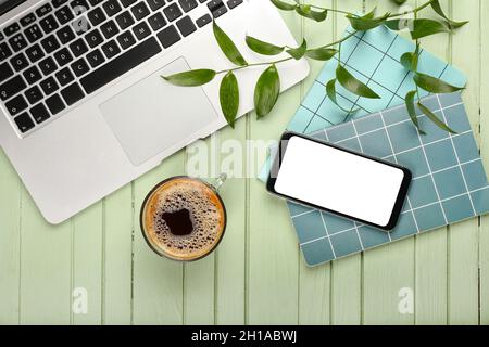 Composition with cup of coffee, laptop, mobile phone and notebook on green wooden background Stock Photo