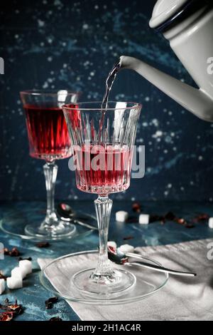Pouring of hot red tea into glass on table Stock Photo