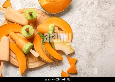 Board with tasty melon popsicles on light background Stock Photo