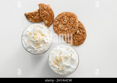 Glasses of tasty latte with nuts on light background Stock Photo