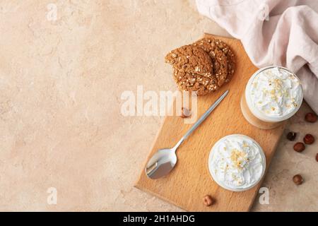Glasses of tasty latte with nuts and cookies on beige background Stock Photo