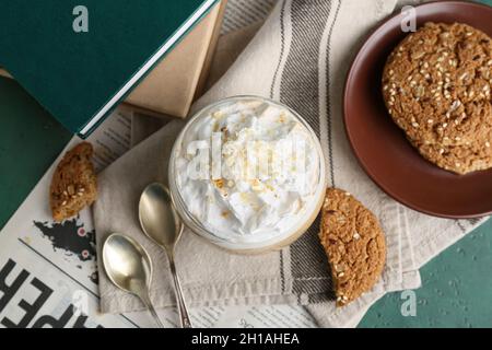 Glass of tasty latte with nuts and cookies on green background Stock Photo