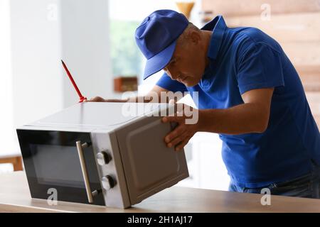 Male worker repairing microwave oven in kitchen Stock Photo